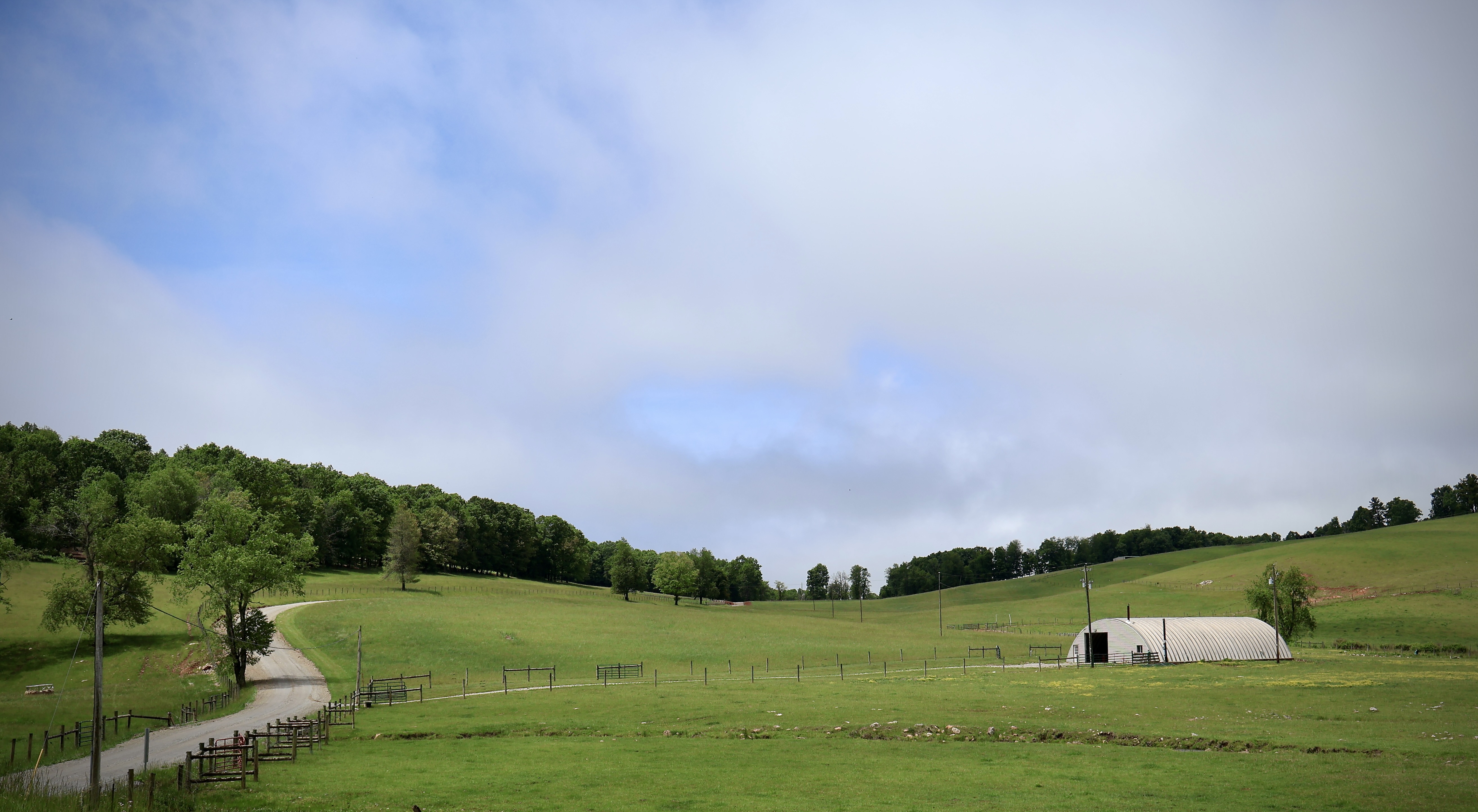 Gravel road winding through green hills toward a white barn