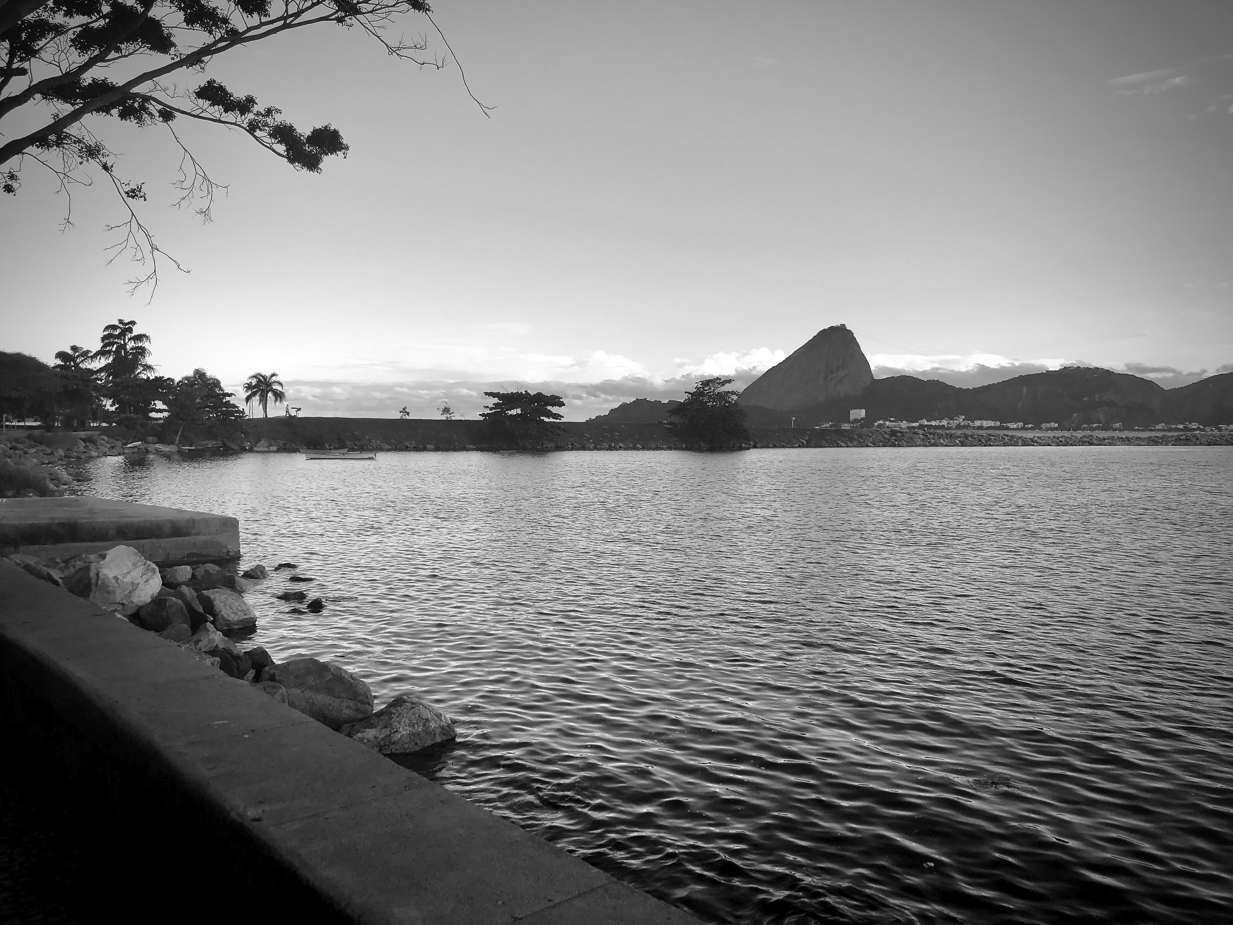 Black and white view of Sugarloaf Mountain silhouetted over a calm bay in Rio de Janeiro